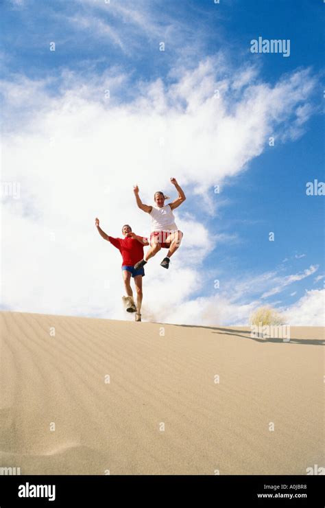 Two Men Leaping From Sand Dunes Stock Photo Alamy