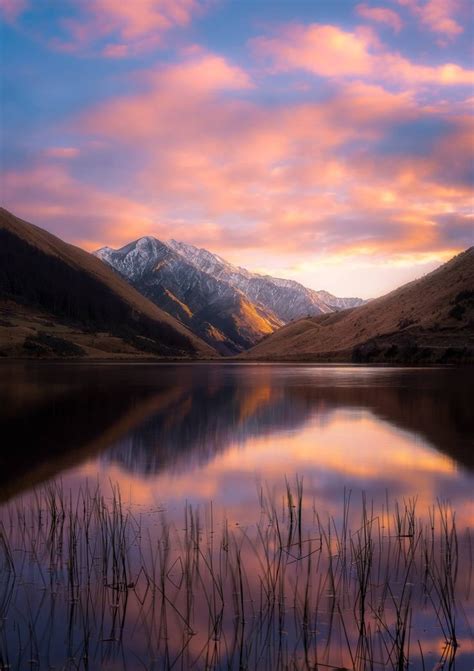 The Mountains Are Reflected In The Still Water At Sunset With Snow
