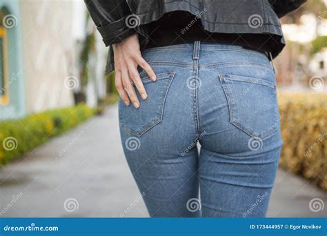 back or buttocks of a beautiful woman in jeans and leather jacket on blur background stock image