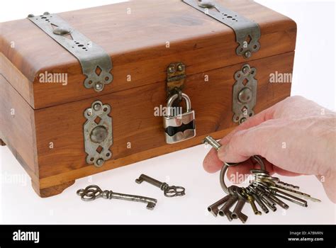 Mans hand searching for the right key to unlock a strong treasure box