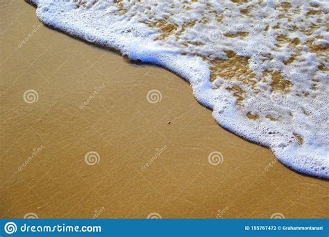 Ocean Wave Washing Up Sandy Beach With Bubbles And Foam Stock Photo