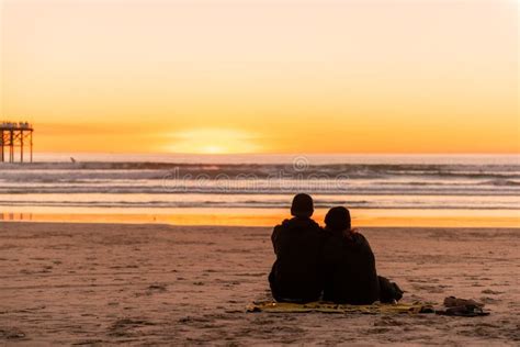 Young Couple Sitting By The Beach Watching Sunset Stock Image Image