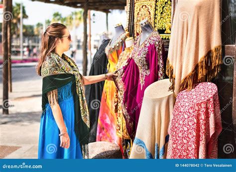Woman In Souk Tourist Looking At Traditional Arabian Dresses And