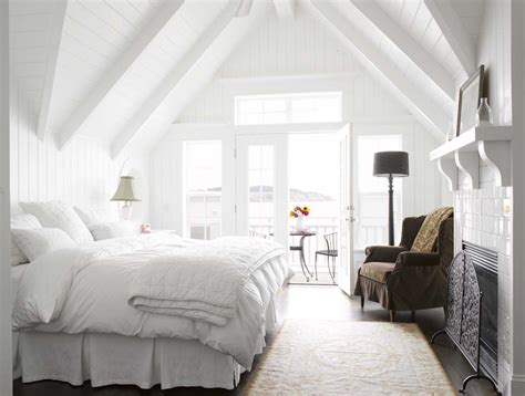 A Bedroom With White Walls And Ceilings Has A Large Bed In The Center