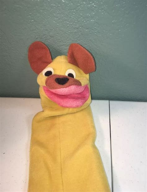 A Stuffed Animal That Is Wearing A Yellow Outfit With Pink Tongue