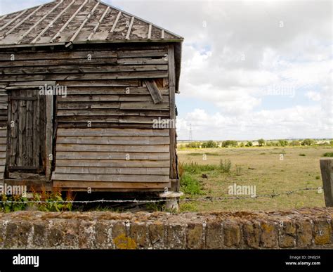 An Image Showing An Old Shack With A Field In The Background Stock