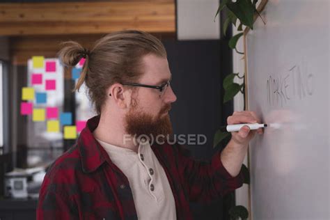 Male Executive Writing On Whiteboard In Office — Small Business