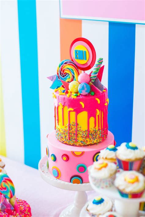 There Is A Colorful Cake And Cupcakes On The Table