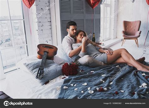 Beautiful Young Couple Embracing While Lying Bed Home Heart Balloons