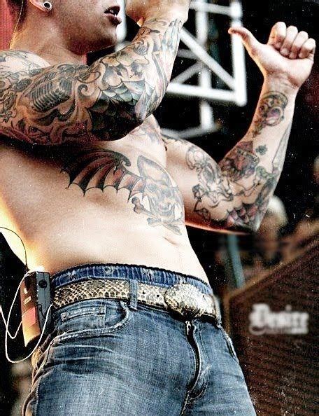 A Man With Tattoos On His Arms And Chest Holding A Microphone In Front Of Him