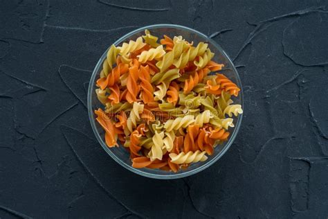 Multicolor Spiral Macaroni Pasta In A Glass Bowl On A Black Textured