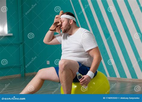 Overweight Man Is Sitting On A Fitness Ball Exhausted After A Hard Training In Group Fitness