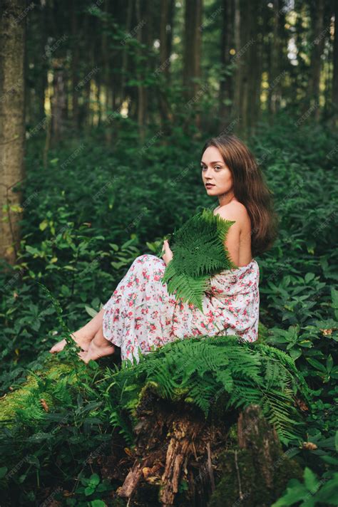 premium photo a cute girl in a floral dress is sitting with a fern bouquet in the forest
