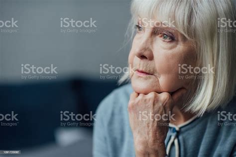 Portrait Of Thoughtful Senior Woman Propping Chin With Hand At Home