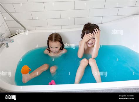 From Above Of Adorable Little Brother And Sister Bathing In Bathtub With Blue Water And Having