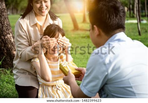 Happy Asian Mother Covering Eyes Of Excited Daughter And Smiling