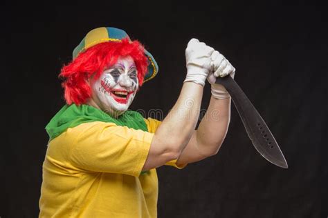 Scary Clown Joker With A Smile And Red Hair With A Big Knife On Stock