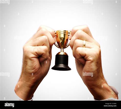 A Pair Of Hands Holding Up A Tiny Trophy In Celebration Of Winning And
