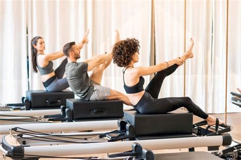 premium photo class of group stretching legs on pilates reformer