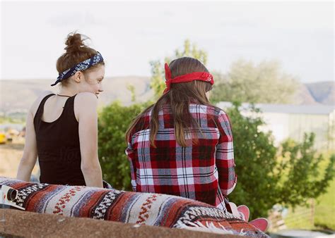Teen Girls Sitting Next Each Other On Blanket Looking Down From Roof
