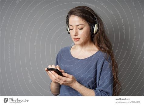 Young Woman Listening To Music With Wireless Bluetooth Headphones And
