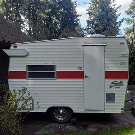 An Old Camper Is Parked In The Driveway