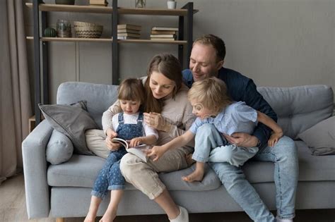 Parents And Kids Sit On Sofa With A Book Stock Image Image Of Kids