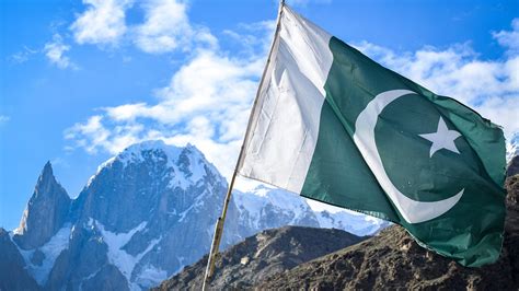 Pakistan Flag In White Covered Mountain Background Under White Clouds