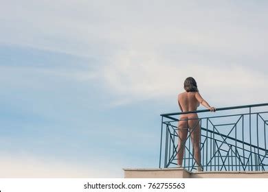 Naked Female Stands On Balcony Opposite Stock Photo
