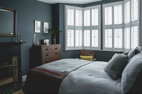 a bedroom with blue walls and white shutters