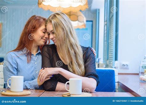 Same Sex Relationships Happy Lesbian Couple Sitting In A Cafe Girls Gently Hold Hands And