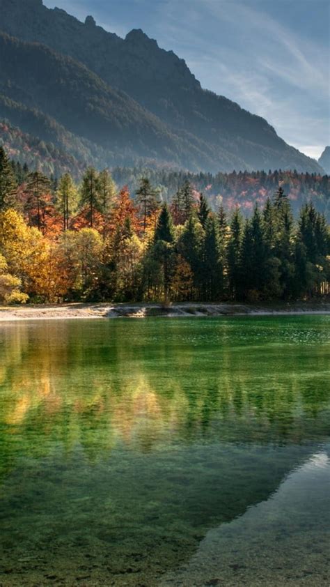 Calm Body Of Water Surrounded With Trees And Mountains