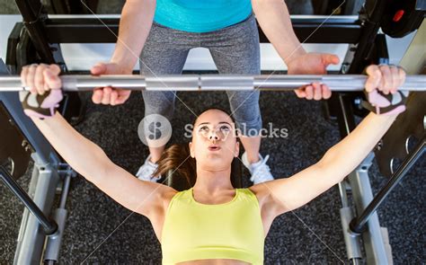 Woman With Her Personal Trainer In A Gym Working Out With Weights Bench Pressing Royalty Free