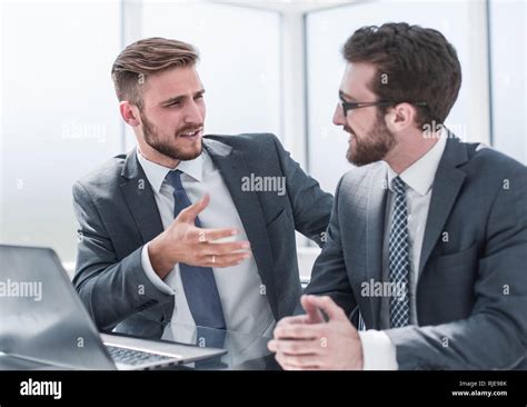 Two Businessmen Talking Sitting At His Desk Stock Photo Alamy