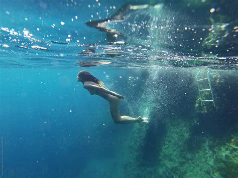 Skinny Girl Swimming Underwater In Clean Blue Sea By Stocksy