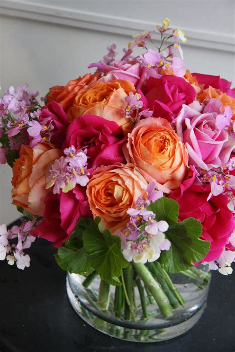 A Vase Filled With Lots Of Pink And Orange Flowers On Top Of A Black Table