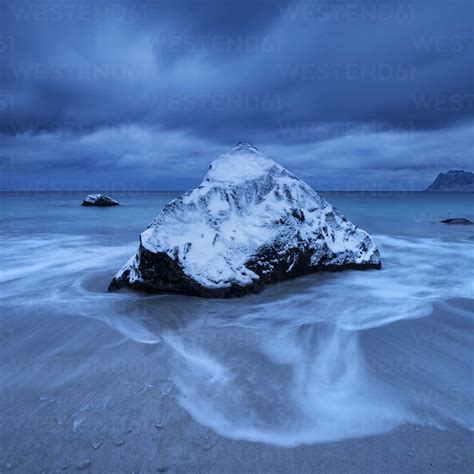 Waves Wash Over Snow Covered Rock In Winter At Myrland Beach Flakstad