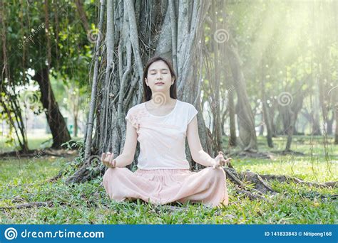 De Aziatische Vrouw Maakt Een Meditatie Onder Grote Boom In De Tuin Voor Goede Gezondheid Stock