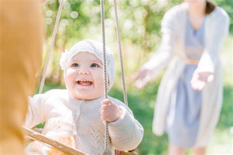 Stylish Young Parents Swings Their Happy One Year Old Daughter On A