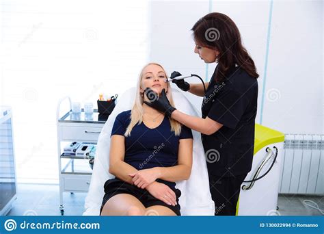 A Cosmetologist Carries Out Procedures On The Patient`s Face With A