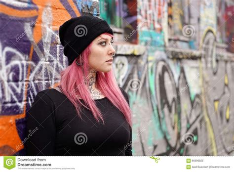 Femme Avec Des Perforations Roses Et Des Tatouages De Cheveux Se Penchant Contre Le Mur De
