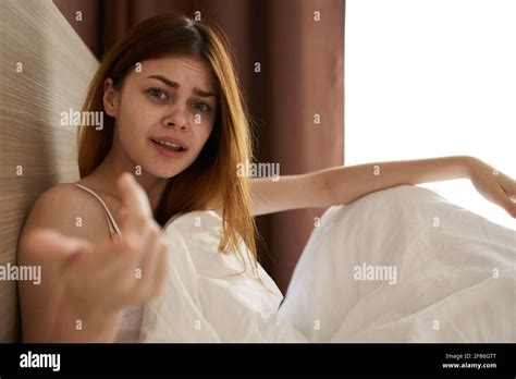 Emotional Woman Lies In Bed Under The Covers And Gestures With Her