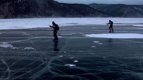 Two Men Are Skating On The Ice Of Frozen Lake Baikal During Beautiful