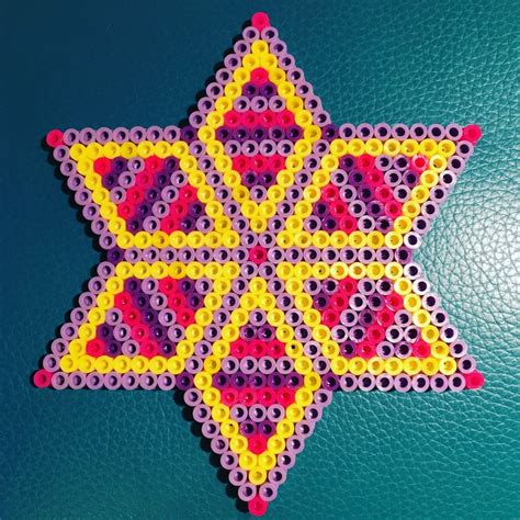 A Star Made Out Of Plastic Beads On A Blue Surface With Red Yellow And