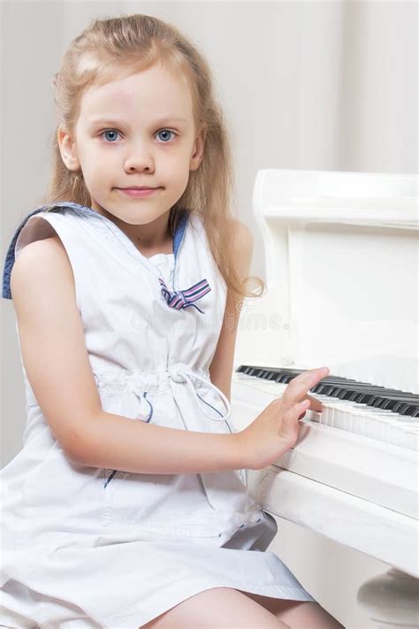 Beautiful Little Girl Is Playing On A White Grand Piano Stock Image