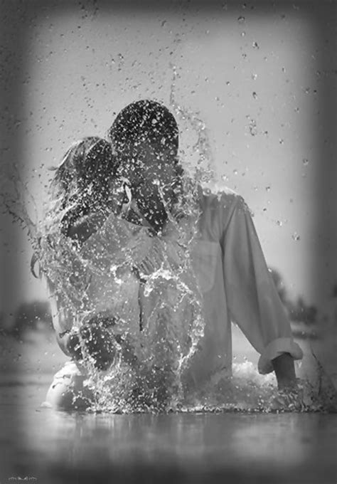 Two People In The Water Splashing Each Other With Their Arms Around One
