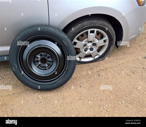 Frontal Flat Tire With A Spare Ready To Be Put On A Silver Car Stock