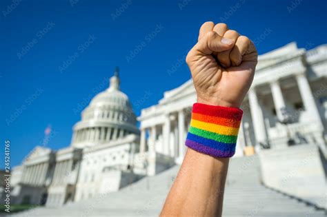 Hand Wearing Gay Pride Rainbow Wristband Making A Power Fist Gesture In Front Of The Us Capitol