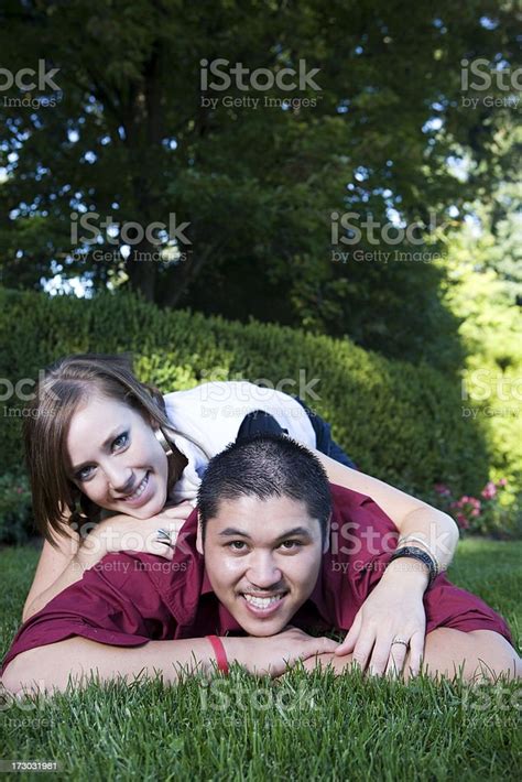 Adorable Interracial Young Couple Portrait Lying On Stomach In Park