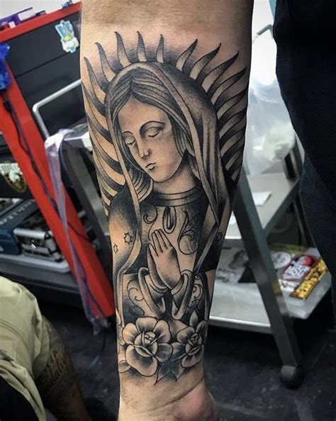 A Person With A Tattoo On Their Arm Holding A Flower And Praying In
